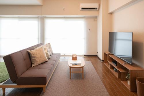 a living room with a couch and a flat screen tv at RIVER WEST Hiroshima 302, 305, 306 - Vacation STAY 54100v in Ōsukachō