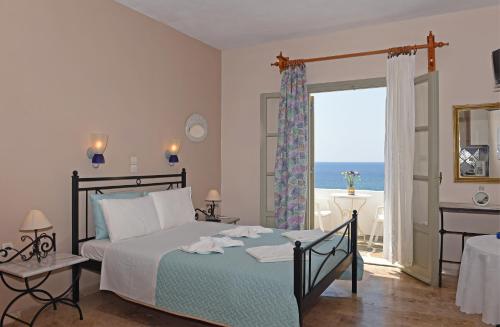 a bedroom with a bed with a view of the ocean at Vrohaki Studios & Rooms in Piso Livadi