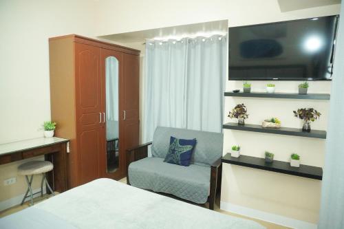 a room with a bed and a chair and a tv at Cozy 2 Bedroom Condo with Balcony for Rent in Iloilo City