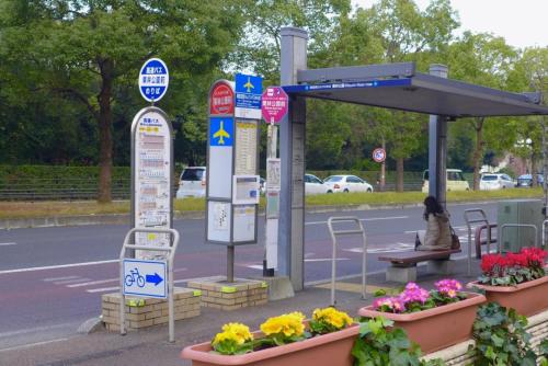 a bus stop with flowers and a person sitting on a bench at Aoisora Aoiumi no guest house - Vacation STAY 74840v in Takamatsu