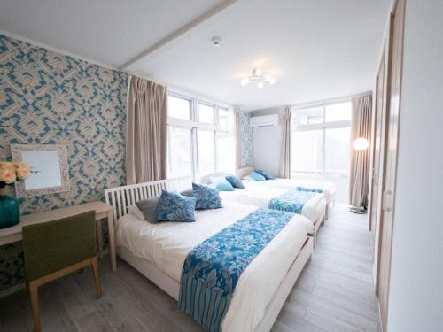 a bedroom with two beds with blue pillows and a desk at Villa East Hana - Vacation STAY 76042v in Nago
