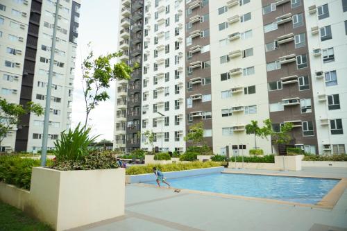 a person walking by a swimming pool in front of tall buildings at Cozy 2 Bedroom Condo with Balcony for Rent in Iloilo City