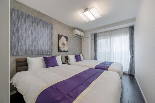 a hotel room with two beds and a window at HOTEL KOMACHI TOKYO Higashi Nippori in Tokyo