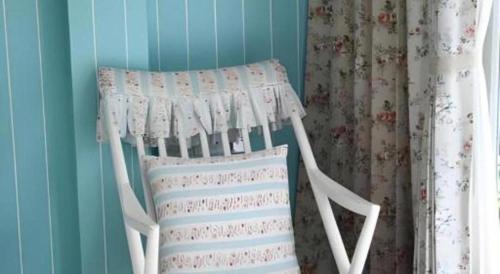 a white rocking chair in a room with curtains at Baan Hmon-Oon in Chiang Mai