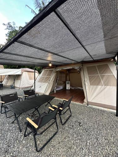 a patio with chairs and a table and a tent at Bukit Langit Campventure in Glagah