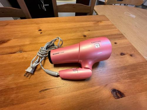 a pink blow dryer on a wooden table at Shibasaki House 1F - Vacation STAY 13848 in Kusatsu