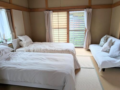 a bedroom with two beds and a couch and a window at Kagawagun - House - Vacation STAY 01716v in Naoshima