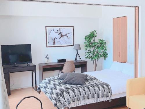 a bedroom with a bed and a tv and a chair at ＥＵＲＯＰＥＡＮ ＨＯＵＳＥ ＲＥＩＳＥＮ - Vacation STAY 10505v in Fukuoka