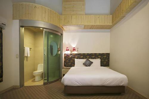 a bedroom with a bed and a bathroom with a toilet at Metro Tourist Hotel Cheonan in Cheonan