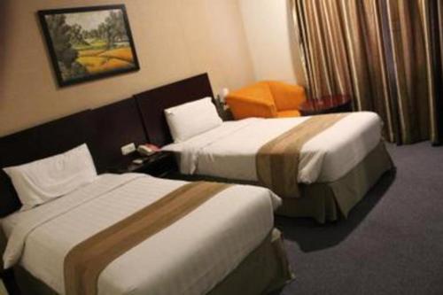 a hotel room with two beds and a chair at Asialink Premier in Karawang
