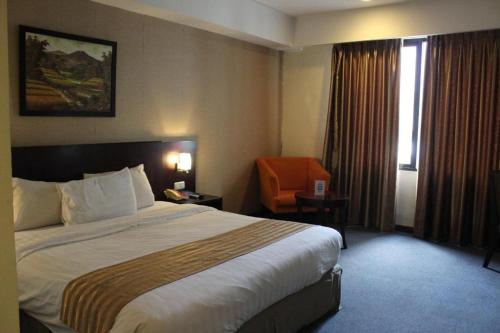 a hotel room with a large bed and a chair at Asialink Premier in Karawang