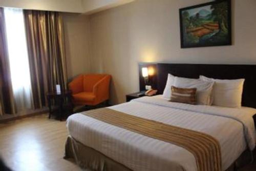 a hotel room with a large bed and a chair at Asialink Premier in Karawang