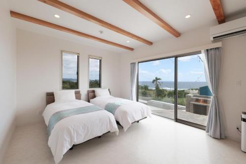 two beds in a bedroom with a large window at Kanasha Building A - Vacation STAY 28224v in Ōkachi