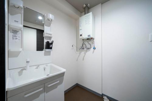 a white bathroom with a sink and a mirror at Starlight in Sapporo