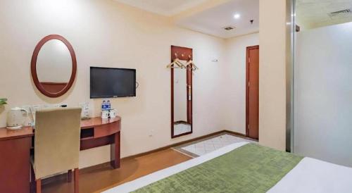 a bedroom with a bed and a vanity and a mirror at GreenTree Inn Beijing East Yizhuang District Second Kechuang Street Express Hotel in Beijing