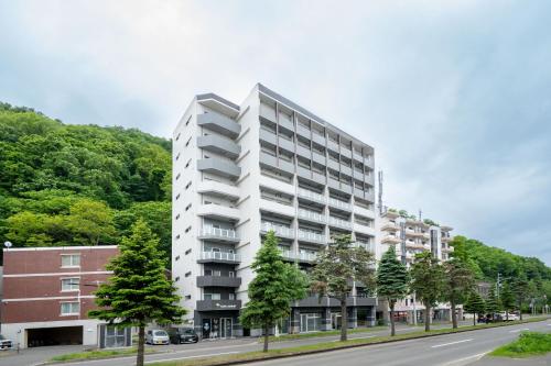 a tall white apartment building on a street at Starlight in Sapporo