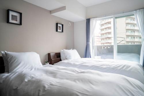 two white beds in a room with a window at Starlight in Sapporo