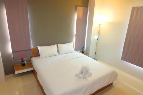 a bedroom with a white bed with a towel on it at The Pride in Nakhon Pathom