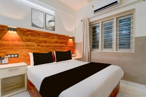 a bedroom with a large bed with a wooden headboard at Super Townhouse Green Field Stadium Karyavattom in Kazhakuttam