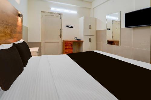 a bedroom with a large white bed and a television at Super Townhouse Green Field Stadium Karyavattom in Kazhakuttam