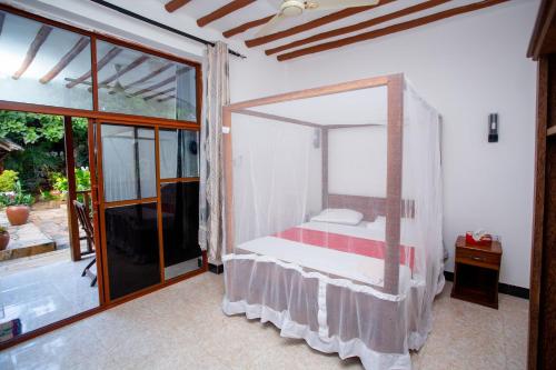 a bedroom with a bed with a mosquito net at Utulivu Bungalow in Nungwi