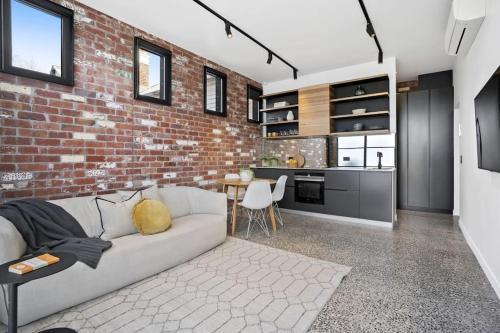 a living room with a couch and a brick wall at The Pix Studio Modern Industrial Stay in Geelong West