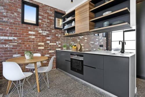 a kitchen with a table and a brick wall at The Pix Studio Modern Industrial Stay in Geelong West