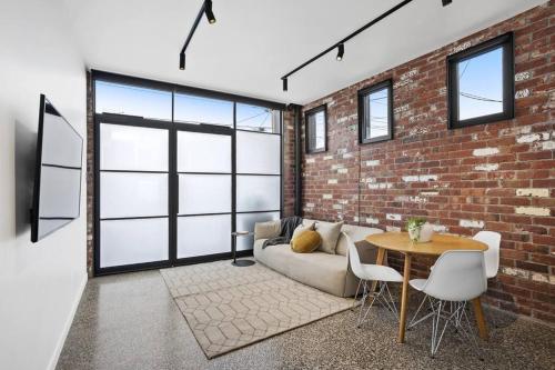 a living room with a brick wall and a couch and a table at The Pix Studio Modern Industrial Stay in Geelong West