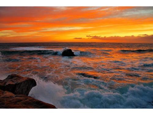 a sunset over the ocean with rocks in the water at Oasis Wadaura - Vacation STAY 89769v in Kamogawa