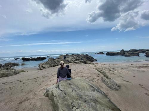 a person sitting on a rock on the beach at Oasis Wadaura - Vacation STAY 89769v in Kamogawa