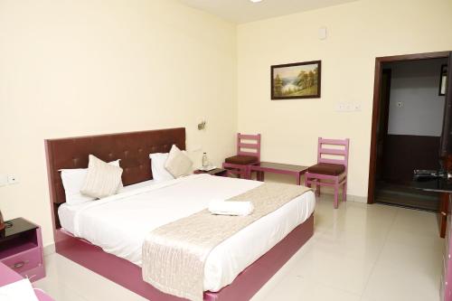 a bedroom with a bed and a table and chairs at SHALOM HOME STAY valparai in Vālpārai