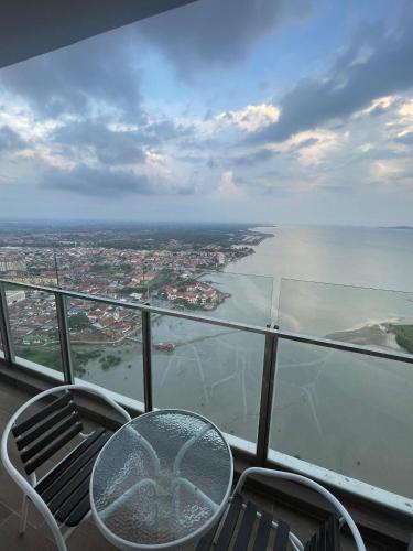 Una mesa y sillas en un balcón con vista al agua. en Silverscape Residence, en Melaka