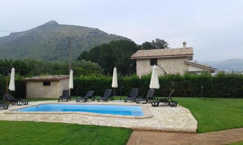 a pool with chairs and umbrellas next to a house at Aia Antica in Monte San Biagio
