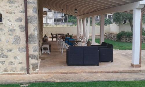 a patio with chairs and tables and a stone wall at Aia Antica in Monte San Biagio