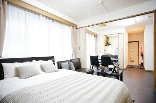 a bedroom with a large white bed and a desk at Maison Tsunami - Vacation STAY 79560v in Naha