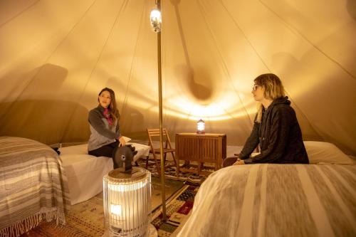 Zwei Frauen sitzen in einem Zelt in der Unterkunft Mt, FUJI SATOYAMA VACATION - Vacation STAY 85277v in Kami-ide