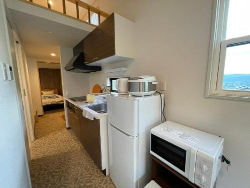 a small kitchen with a refrigerator and a microwave at Camp Field Kijimadaira - Vacation STAY 85297v in Nakamachi
