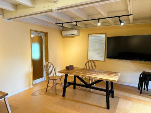 a dining room with a table and chairs and a flat screen tv at Otomie Log House - Vacation STAY 69826v in Kimitsu