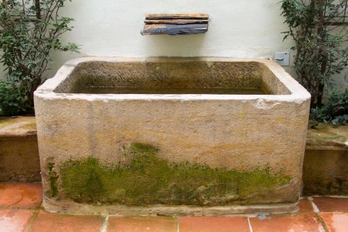 an old stone tub sitting next to a wall at Hotel Casa de la Vega in Bogotá