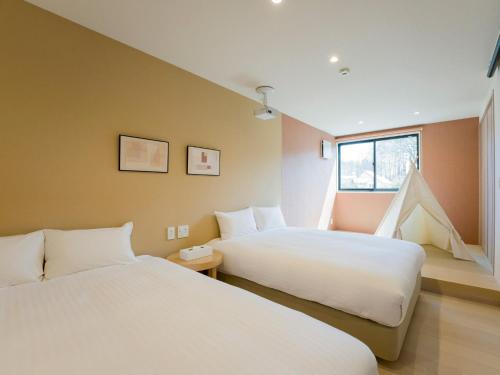 ein Schlafzimmer mit zwei Betten und einem Fenster in der Unterkunft Rakuten STAY VILLA Yatsugatake - 104 Family Room Pets Friendly - in Hokuto