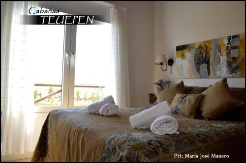a bedroom with a bed with towels on it at Cabañas Teuepen in El Calafate