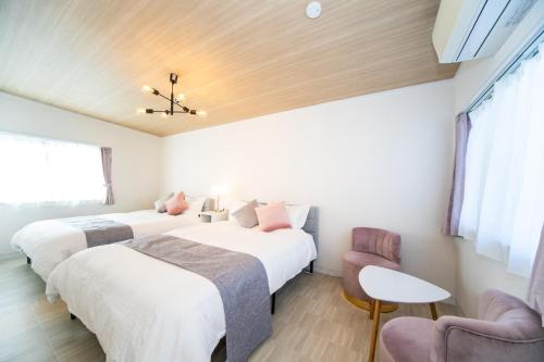 two beds in a room with two chairs and a table at ナガシマリバーサイドリゾート - Vacation STAY 94113v in Kuwana