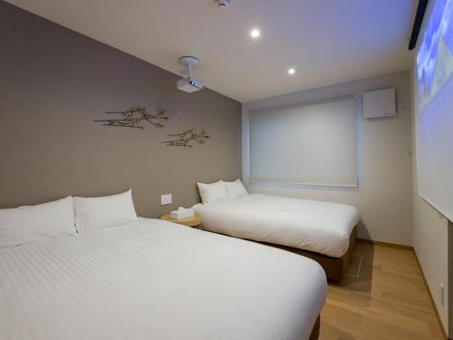 two beds in a small room with a tv at Rakuten STAY VILLA Yatsugatake - 108 Simple Modern Pets Friendly - in Hokuto