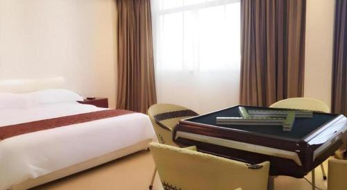 a hotel room with a bed and a suitcase on a chair at Jian Guo Grand Hotel in Vientiane