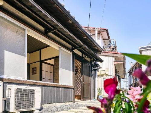a building with a window and pink flowers in the foreground at Kokoyui Guest House Shingu - Vacation STAY 03207v in Shingu
