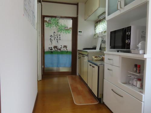 a kitchen with a door leading to a kitchen with white cabinets at SORAMACHI - Vacation STAY 14338 in Takayama