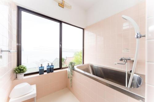 a bathroom with a tub and a sink and a window at Ａｗａｊｉ Ｓｅａｓｉｄｅ Ｖｉｌｌａ ｉｎ Ｇｏｓｈｉｋｉ - Vacation STAY 98416v in Sumoto
