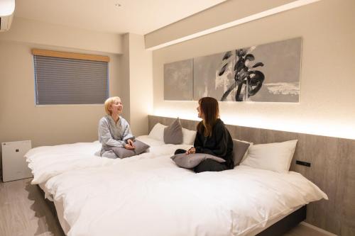 two women sitting on a large bed at ONE WORLD Sakaisuji Honmachi - Vacation STAY 09657v in Osaka