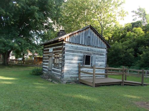 an old wooden out house with a porch in the grass at Melody Motor Lodge in Connellsville