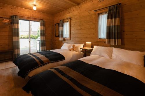 zwei Betten in einem Zimmer mit Holzwänden in der Unterkunft HERMANN Teddy Collectors' House - Vacation STAY 06872v in Kutsukake